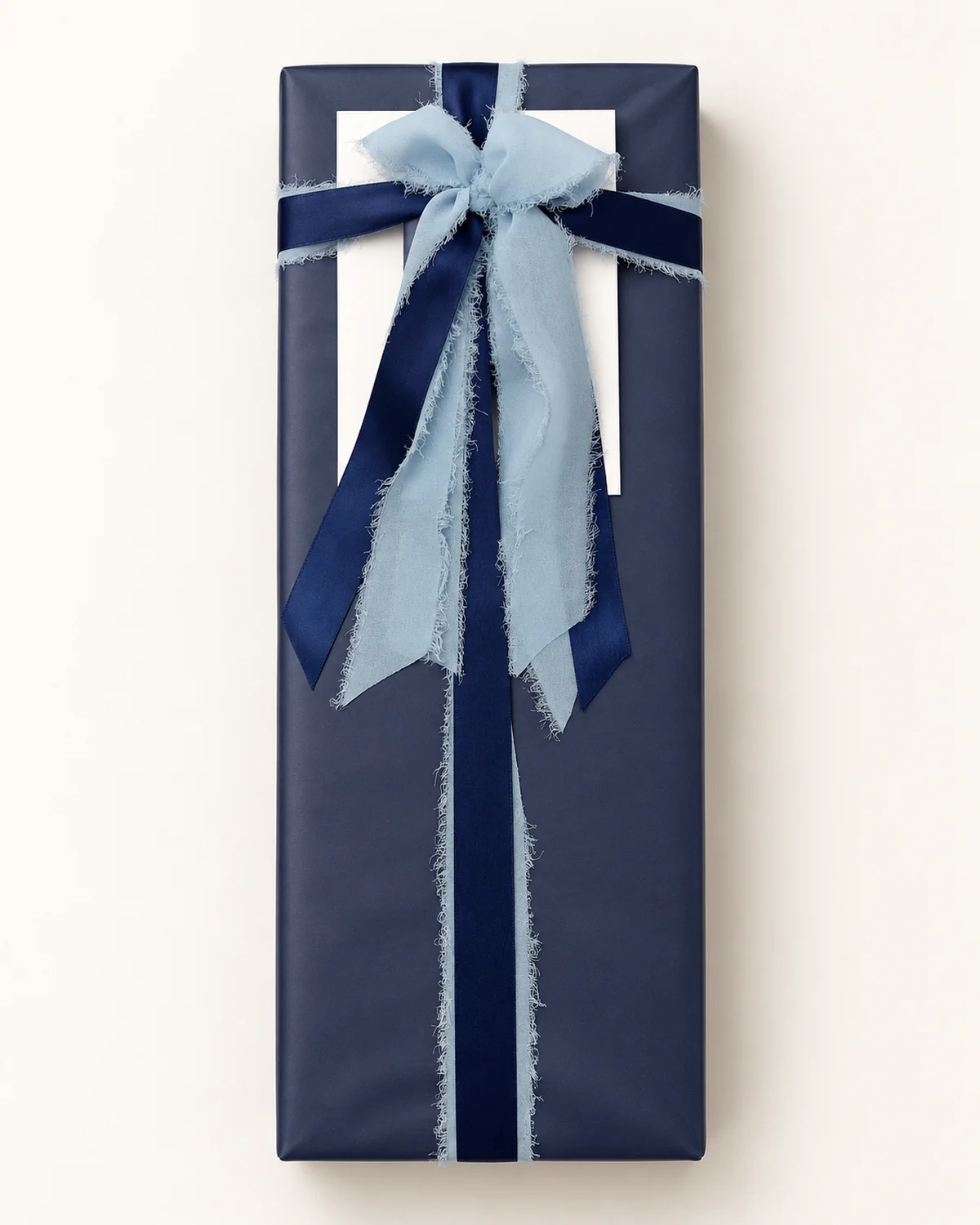 Gift wrapped in navy paper with a navy satin and pale blue chiffon bow by All Wrapped Up